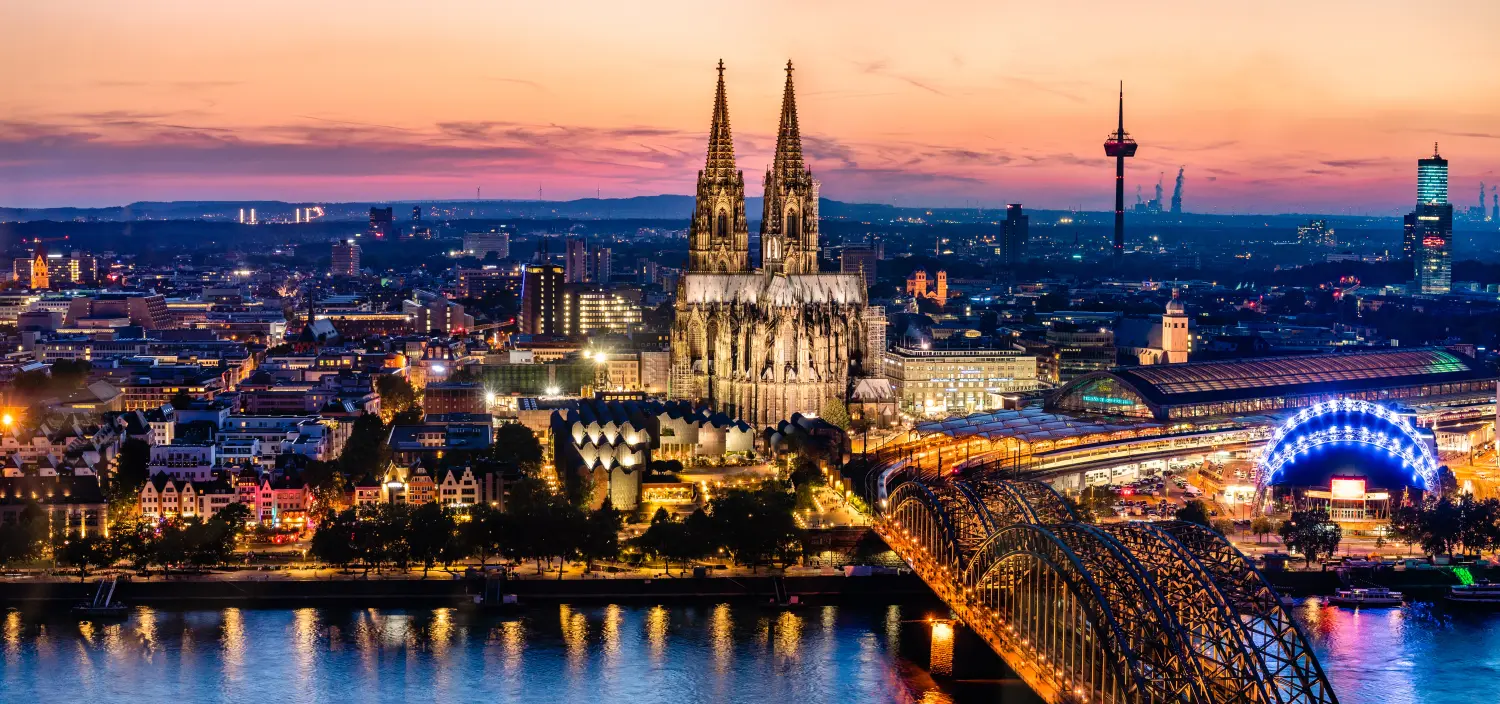 Wunderschöne Nachtlandschaft mit dem gotischen Kölner Dom, der Hohenzollernbrücke und dem Rhein bei Sonnenuntergang und blauer Stunde in Köln